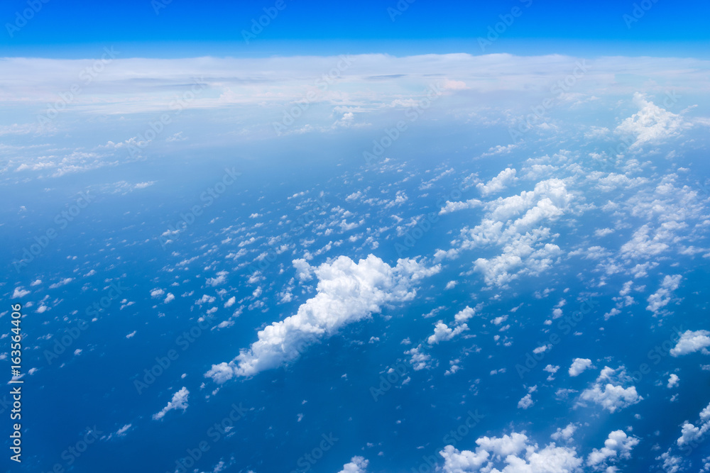 Naklejka premium Flying into blue sky and sea of fantasy row clouds and Wing of airplane with skyline top view as look from window airplane, during flight space for text message, frame or traveling idea concept