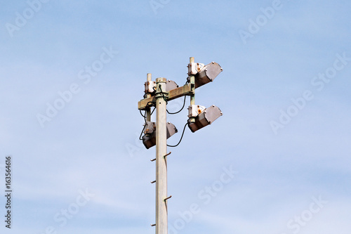 Stadium floodlight tower with reflectors with blue sky. Lighting pole tower at the sports stadium and ground. Big lamp and light stadium poles or sports lighting. Flood light pole in the spotlight.