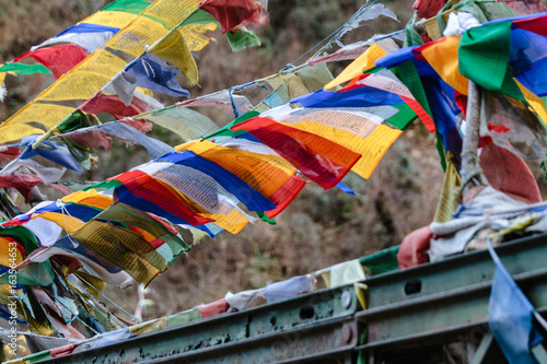 Tear colorful Tibetan prayer flags waving and swaddled with bridge over frozen river at Thangu and Chopta valley in winter in Lachen. North Sikkim, India. photo