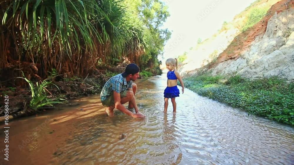 Father Washes Small Girl Hands in Fairy Stream Water