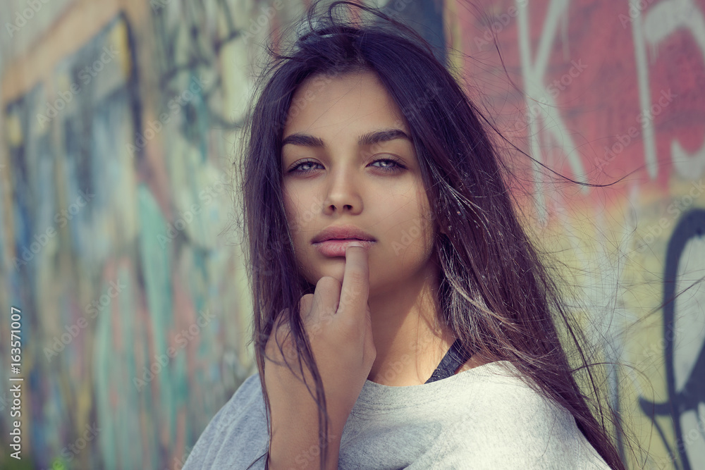 Obraz premium Sexy pretty and successful. Closeup portrait head shot beautiful brunette young woman isolated colorful graffiti background wall. Positive human emotion face expression feeling life perception concept
