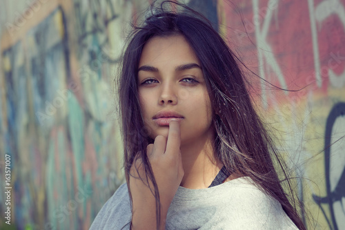 Sexy pretty and successful. Closeup portrait head shot beautiful brunette young woman isolated colorful graffiti background wall. Positive human emotion face expression feeling life perception concept