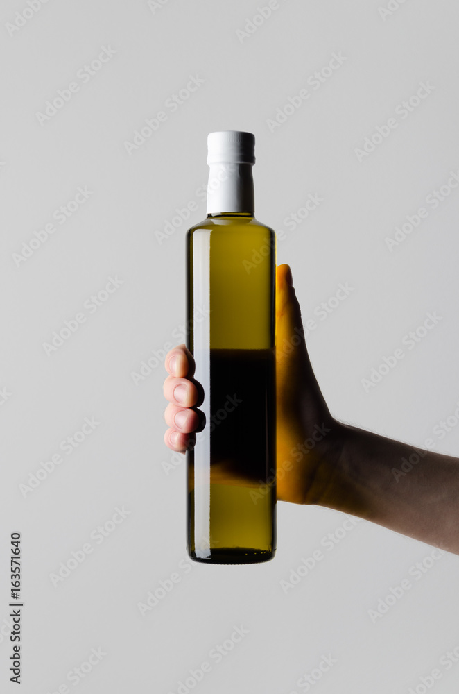 Olive / Sunflower / Sesame Oil Bottle Mock-Up - Male hands holding a oil bottle on a gray background Olive / Sunflower / Sesame Oil Bottle Mock-Up - Male hands holding a oil bottle on a gray background