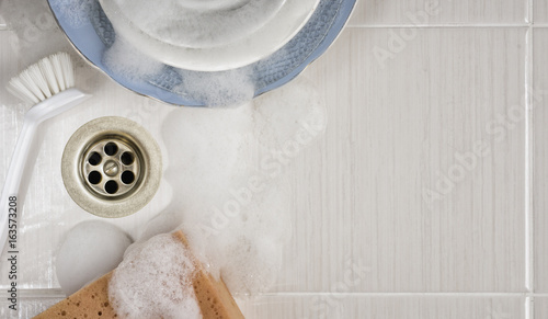 Obraz na plátně Dishes in the sink with a brush and sponge