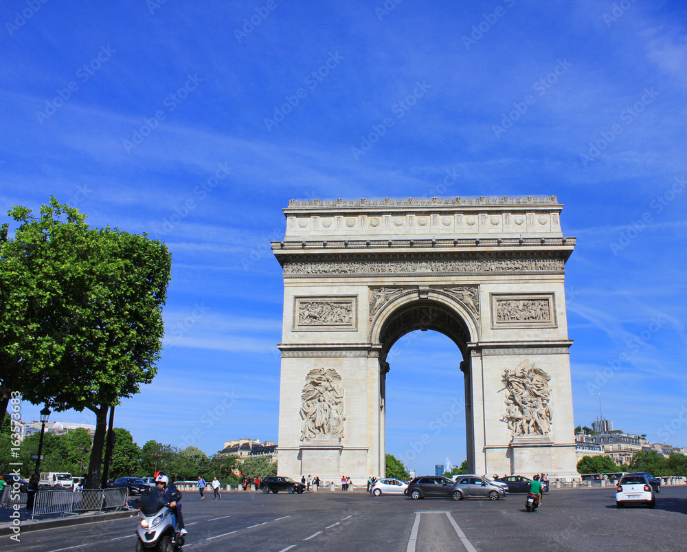 Arc de Triomphe popular top attraction in city of Paris, France. View from Champs Elysees street to Place Charles de Gaulle. Beautiful summer day scene with clear blue sky background.