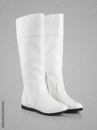 Pair of tall female white boots on gray background with clipping path