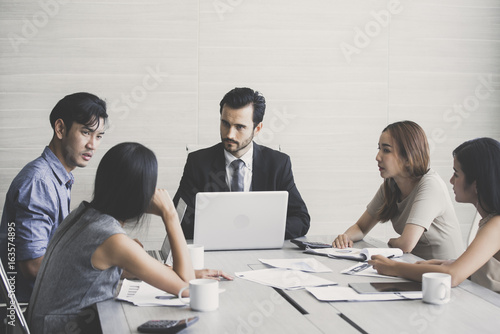 Young Business people working together with serious emotion. Business people takling in modern office. business people working concept © Bavorndej