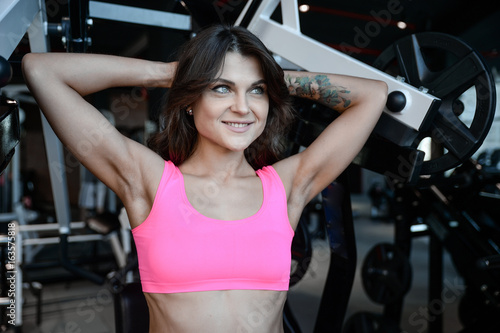 Fitness girl with a beautiful smile posing and exercise in the gym.