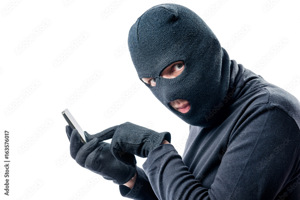 Hacker hacks data from a mobile phone on a white background in a mask