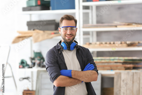 Fotografie Young smiling carpenter standing with crossed hands in workshop
