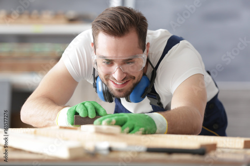 Young carpenter sanding tim...
