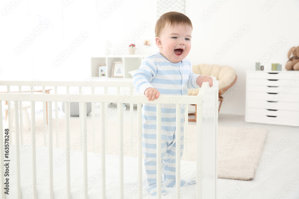 Cute little baby standing in crib at home Cute little baby standing in crib at home