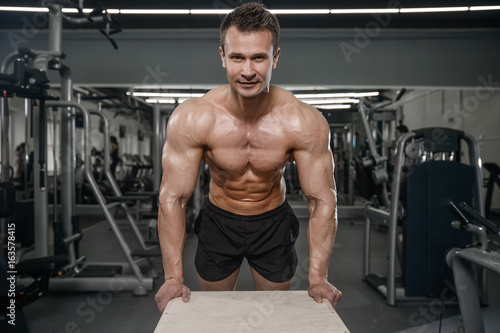 Caucasian handsome fitness model training in the gym. Man on diet flexing muscles