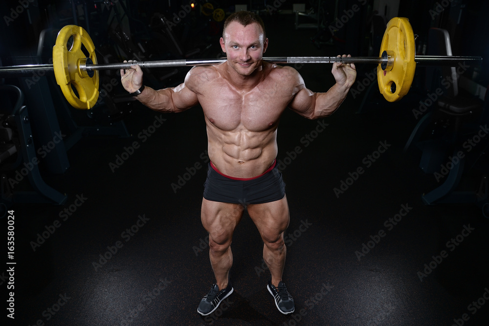 Brutal strong bodybuilder man pumping up muscles and train gym Brutal strong bodybuilder man pumping up muscles and train gym