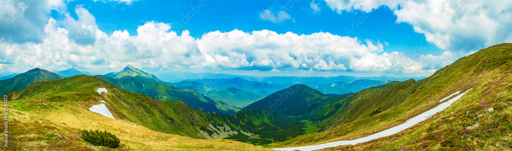 Panoramic view of the sky and mountain ridges from the top of the mountain in a sunny summer day