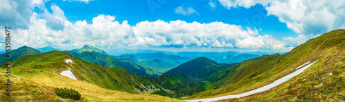 Panoramic view of the sky and mountain ridges from the top of the mountain in a sunny summer day
