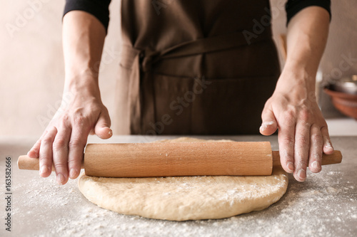 Woman rolling dough for cinnamon rolls on kitchen table © Africa Studio