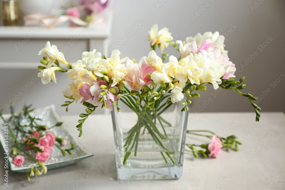 Fototapeta premium Beautiful bouquet with freesia flowers in glass vase on blurred background