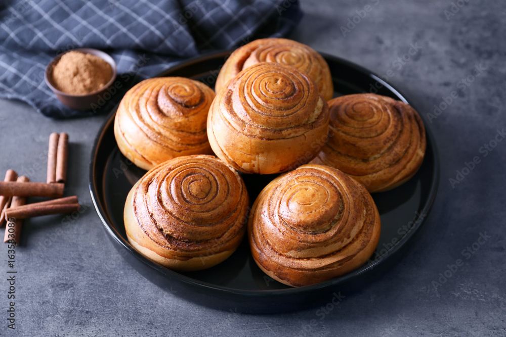 Black round plate with yummy cinnamon rolls on kitchen table Black round plate with yummy cinnamon rolls on kitchen table