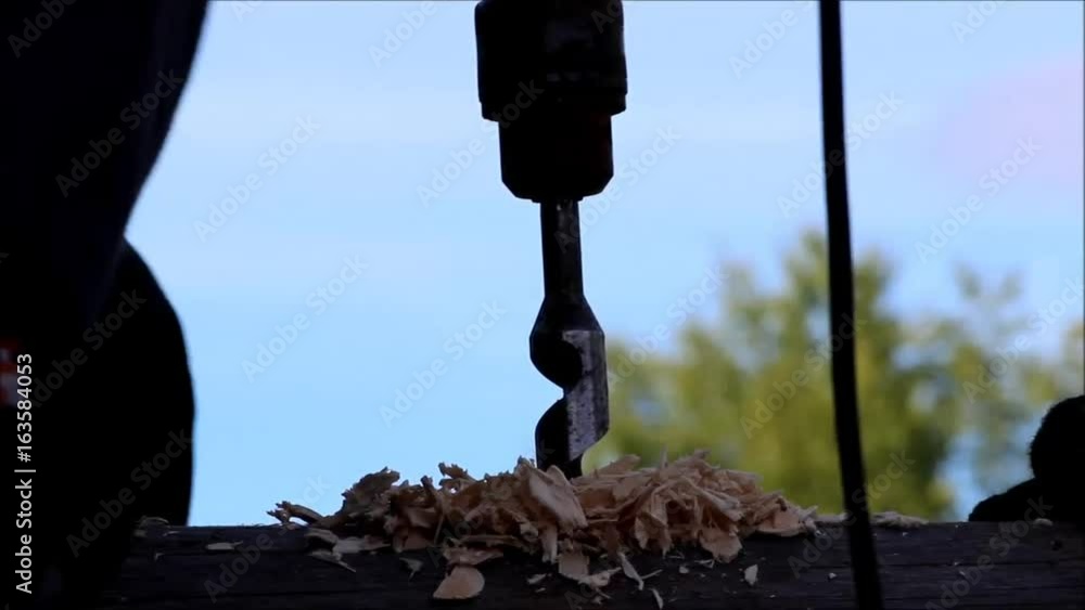 The worker collects the frame and drills a hole in a log for dowel