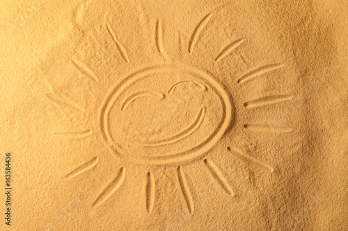 Sun drawn on sea sand, closeup view