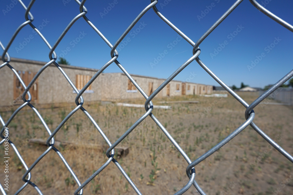 Fototapeta premium abandoned homes behind chain link fence