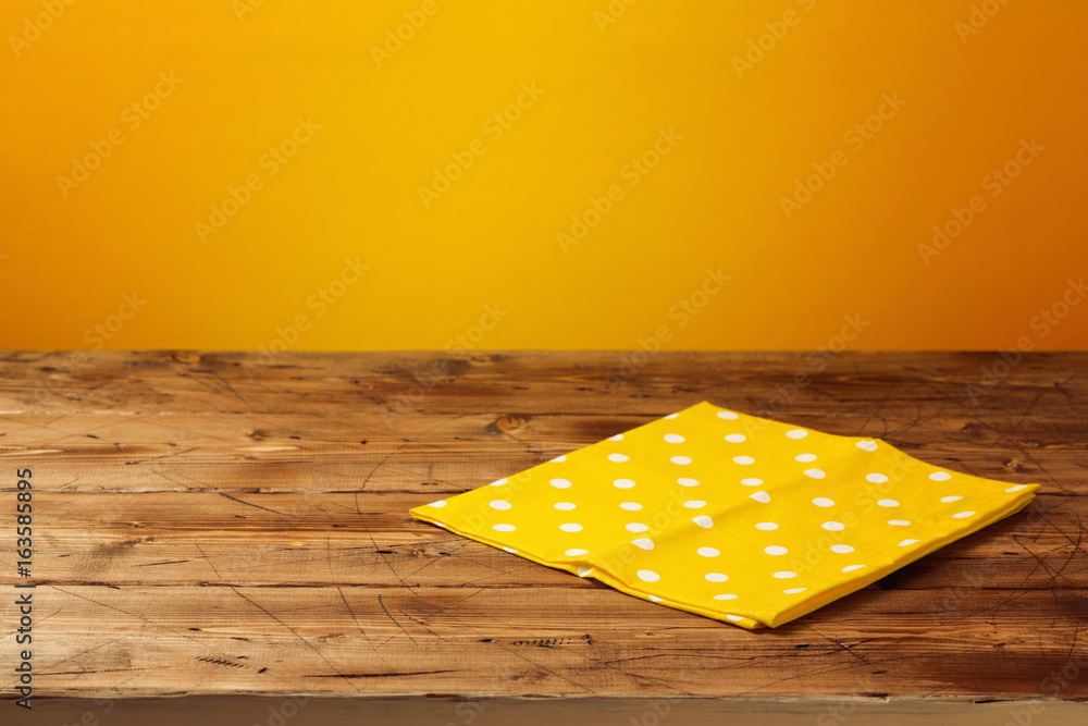 Naklejka premium Empty wooden table with tablecloth over yellow background. Autumn season concept