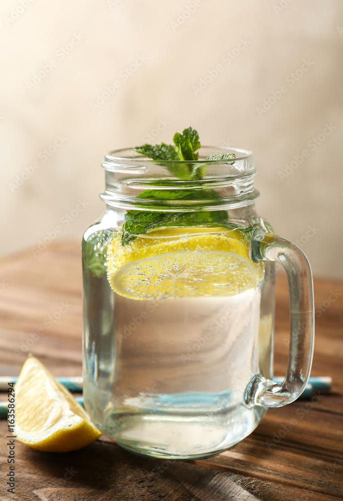 Refreshing lemon water in glass mason jar on wooden table Refreshing lemon water in glass mason jar on wooden table