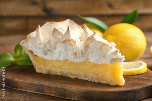 Piece of yummy lemon meringue pie on wooden table
