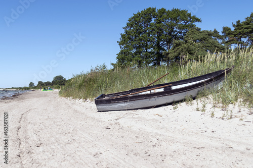 En liten båt av trä liggande på en sandstrand