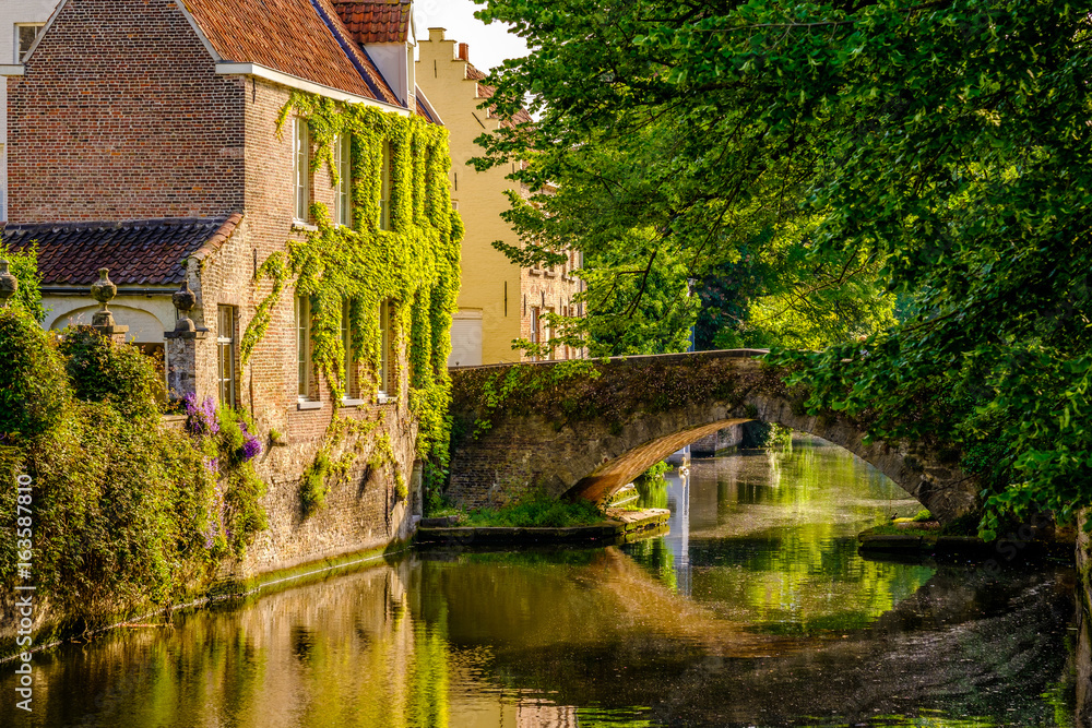 Naklejka premium Pejzaż Brugii (Brugge) z kanałem wodnym i mostem