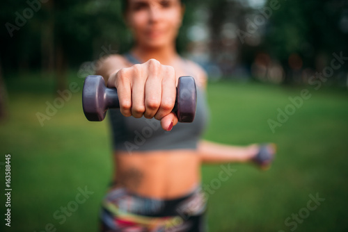 Sporty girl exercise with dumbbells in park