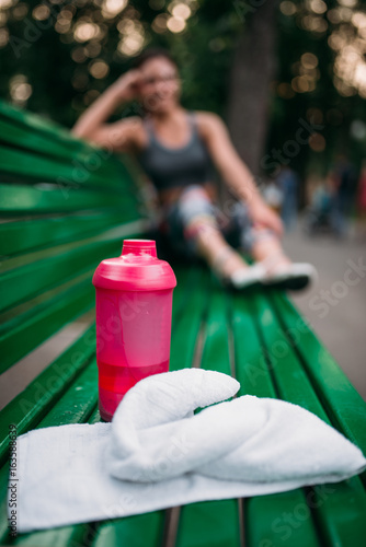 Sport bottle and towel on a bench in summer park