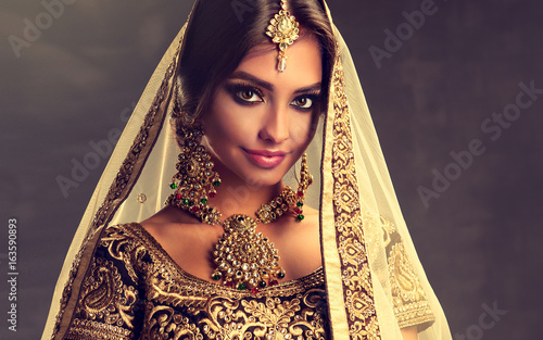 Portrait of beautiful indian girl. Young hindu woman model with golden kundan jewelry set . Traditional Indian costume lehenga choli . 
