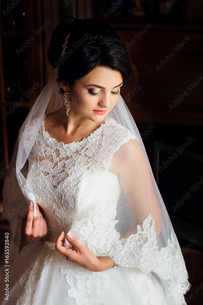 Gorgeous bride holding her veil around her body Gorgeous bride holding her veil around her body