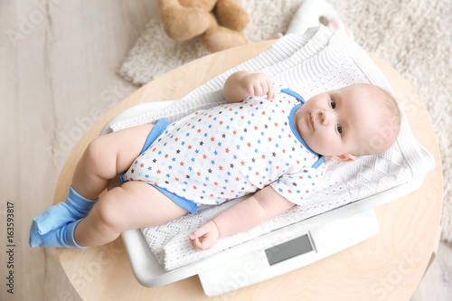 Baby lying on scales in room