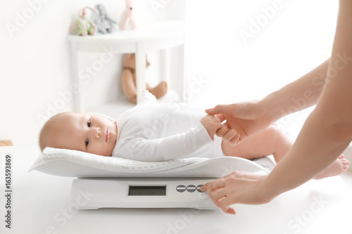 Mother weighting baby on sc...