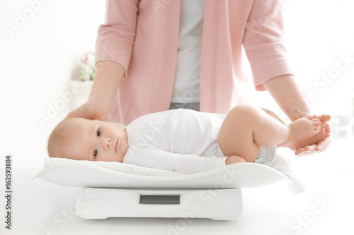 Mother weighting baby on sc...