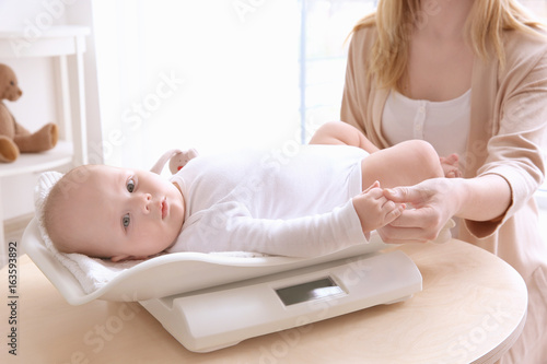 Mother weighting baby on sc...