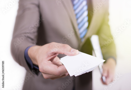 Close up view of a young businessman holding his business camera toward the camera white background. Copy space on the card. Close-up of a man giving a business card.