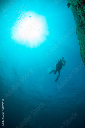 Wallpaper Mural Scuba Divers, silhouettes against sunburst, in the ocean beside coral reef Torontodigital.ca