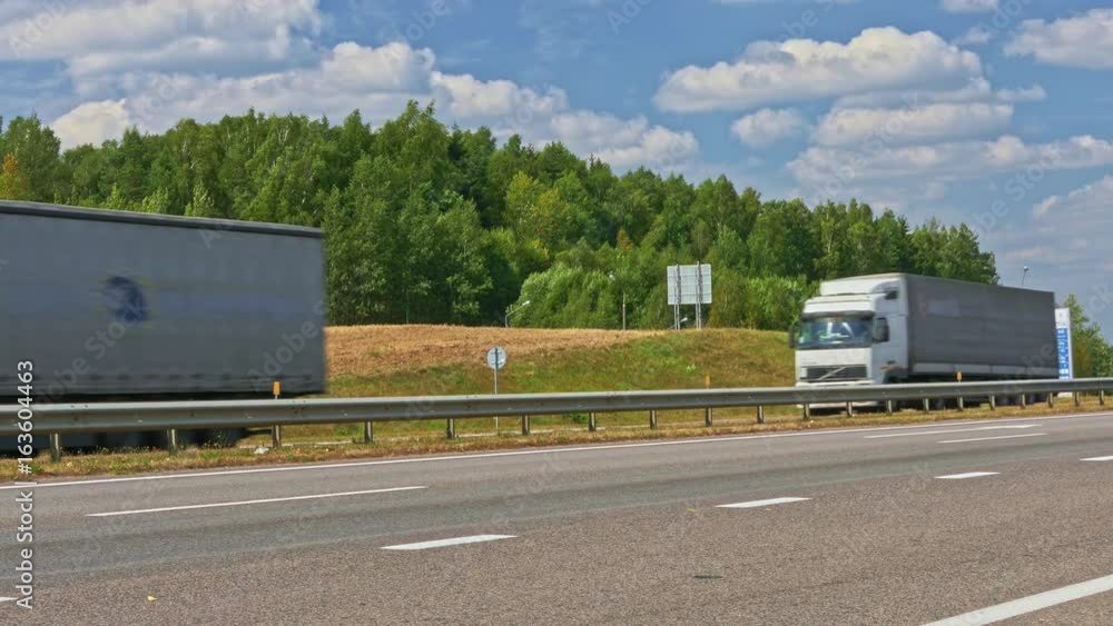 Three cargo trucks covered with tarpaulin travel on intercity highways. Three cargo trucks covered with tarpaulin travel on intercity highways.