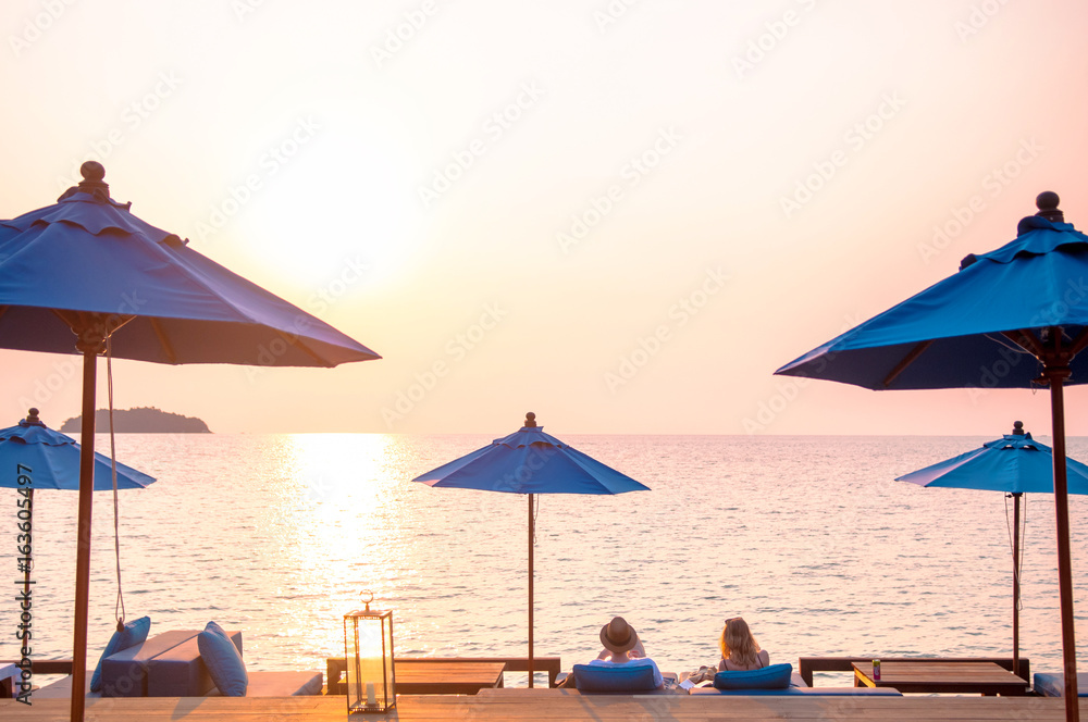 Romantic Sunset, beach umbrellas and honeymoon couple.