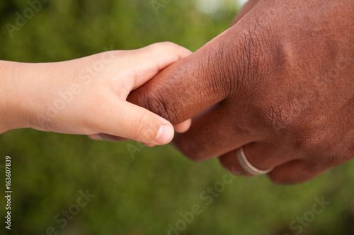 Close up of a father and son holding hands. © digitalskillet1