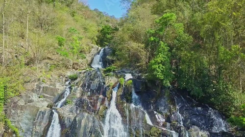 Flycam Removes from Rocky Waterfall against Blue Sky photo