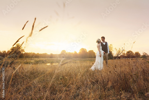 Newlyweds standing in the field with ears