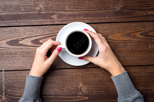 Overhead shot of woman's hands holding cup of coffee
