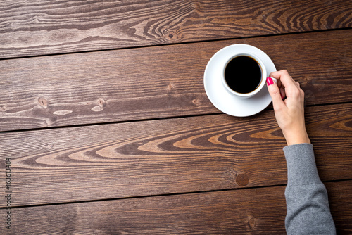Overhead shot of woman's hands holding cup of coffee