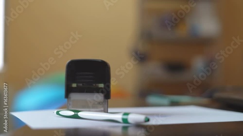 Young woman working in office with papers. Deaet approval by stapping with a seal on paper. Diverse ways to press photo