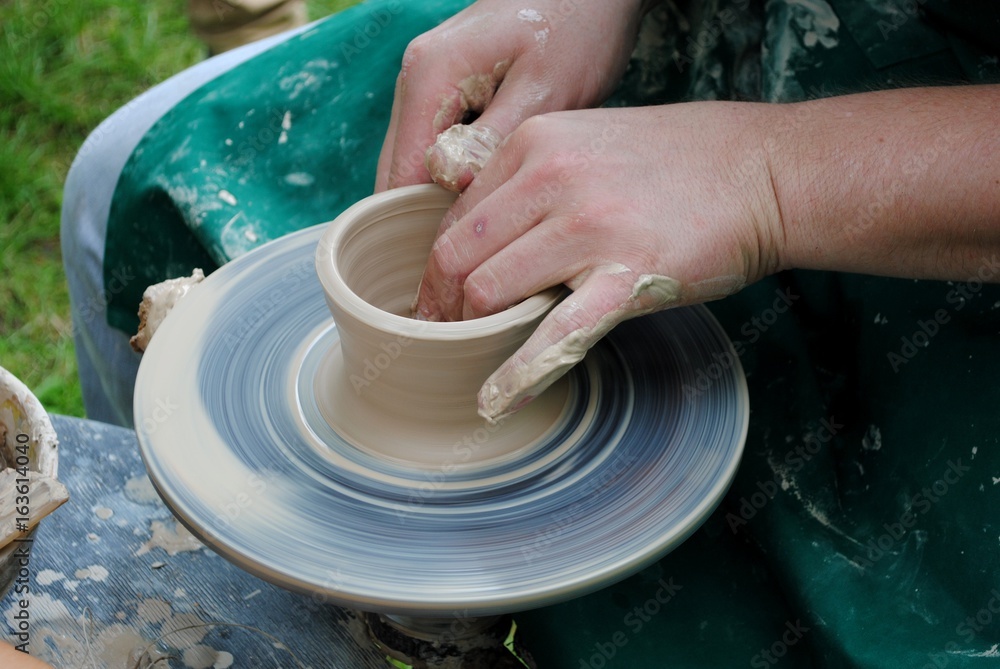 Potter's hands guiding child's hands to help him to work with the pottery wheel Potter's hands guiding child's hands to help him to work with the pottery wheel
